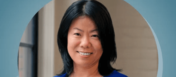 Professional headshot of a woman in a blue top smiling warmly against a soft-focus background